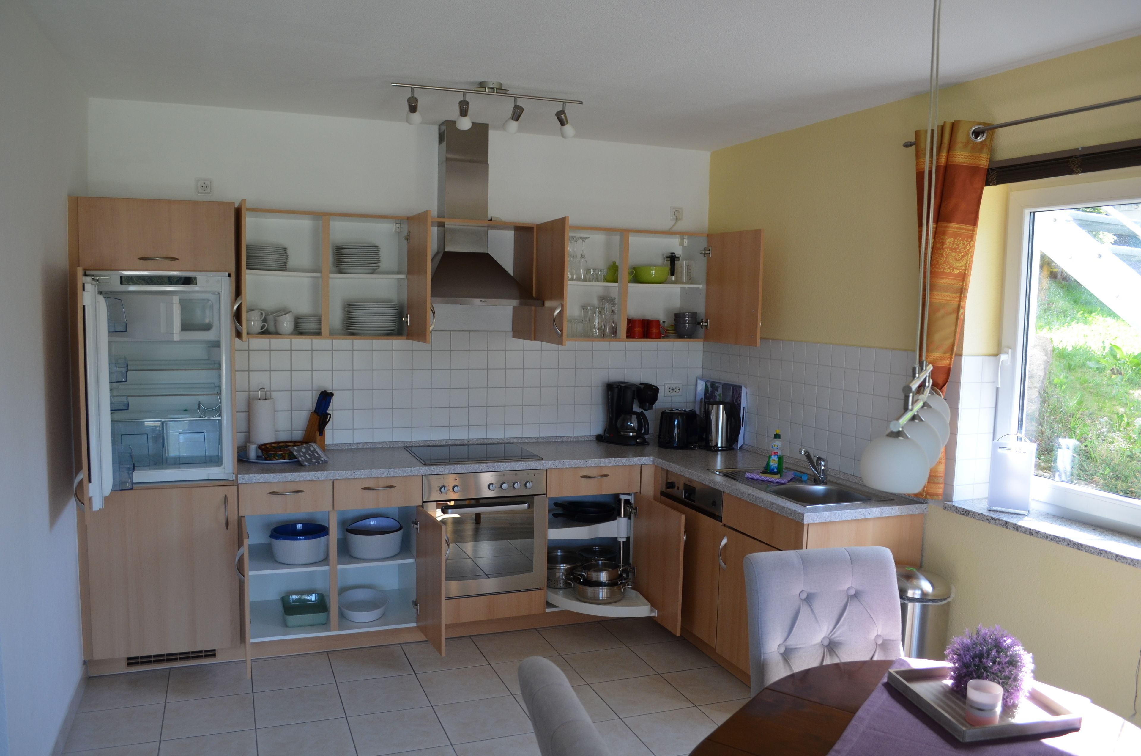 A kitchen with wooden cabinets, a built-in oven, a sink, and a window with a view of greenery.