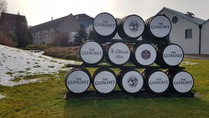 A stack of barrels with 'The Glenlivet' branding, set against a building backdrop. - Linn of Avon Holiday Cottages (Ballindalloch)
