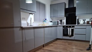 A modern kitchen with grey cabinets, a microwave, a kettle, and a dishwasher. - Linn of Avon Holiday Cottages (Ballindalloch)