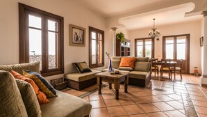 Amplia sala de estar con sofá, mesa de centro y comedor con sillas y mesa.