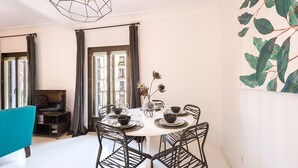A dining area with a round table set for four, surrounded by black chairs. A vase with flowers is on the table, and there is a painting of leaves on the wall. - Genteel Home Chueca - Three Bedroom Apartment, Sleeps 5 (Madrid)