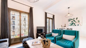 A modern living room with a teal sofa, a wooden coffee table, and a TV. - Genteel Home Chueca - Three Bedroom Apartment, Sleeps 5 (Madrid)