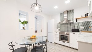 A modern kitchen with a round glass table, four chairs, a built-in oven, and a microwave. - Genteel Home Chueca - Three Bedroom Apartment, Sleeps 5 (Madrid)