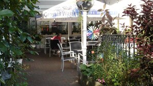 An outdoor seating area with tables and chairs, a sign for 'Grosses Wasser', and a decorative wheel. - Fränkischer Gasthof Lutz (Giebelstadt)