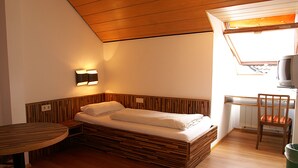 A compact room with a bed, a small table, a chair, and a television. - Fränkischer Gasthof Lutz (Giebelstadt)