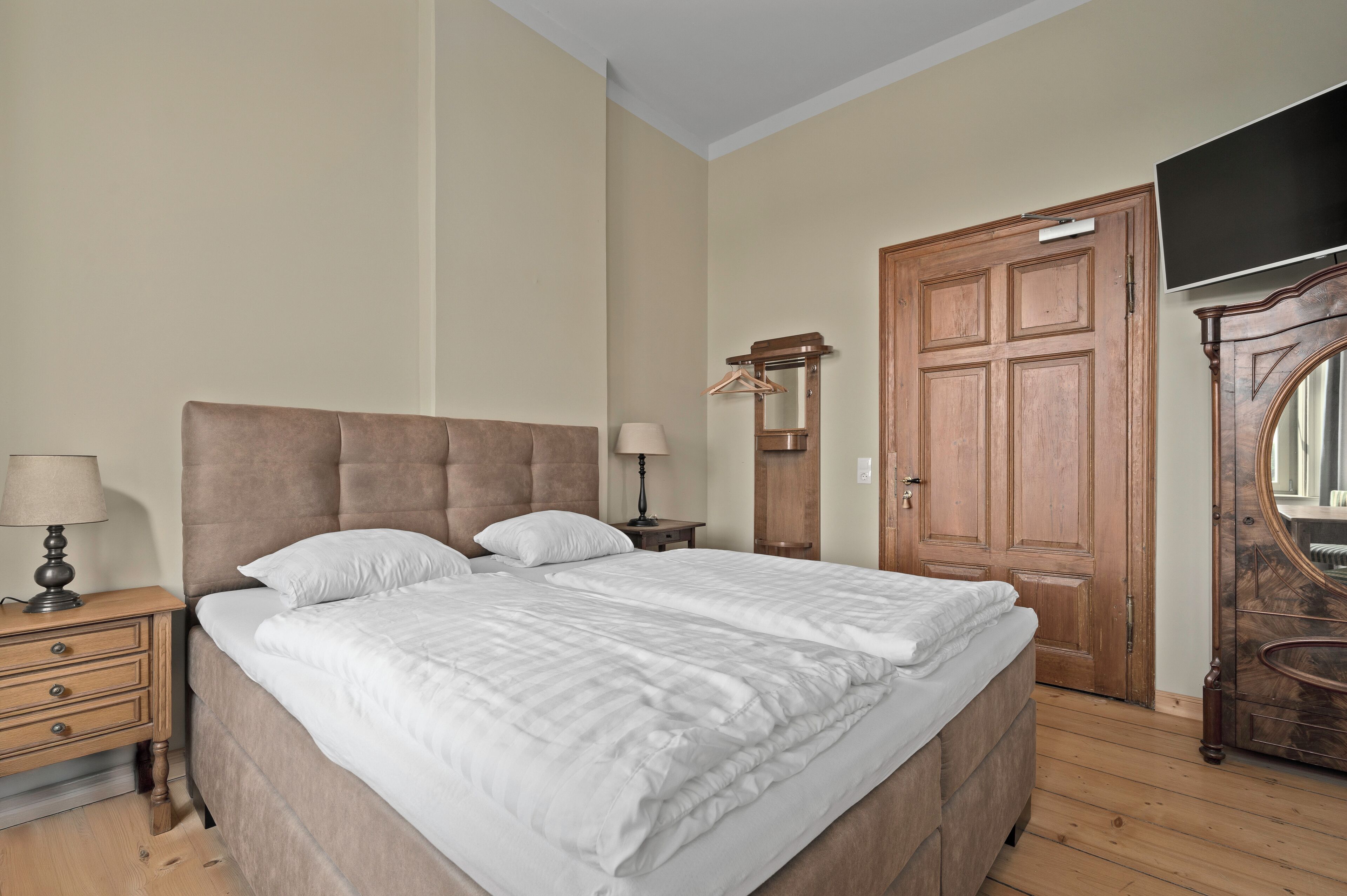 Un dormitorio con una cama grande, un armario de madera y una televisión.