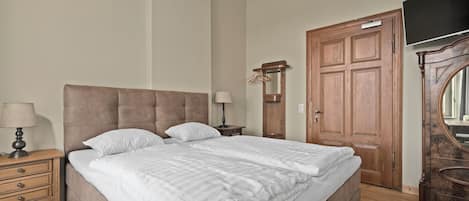 Un dormitorio con una cama grande, un armario de madera y una televisión.