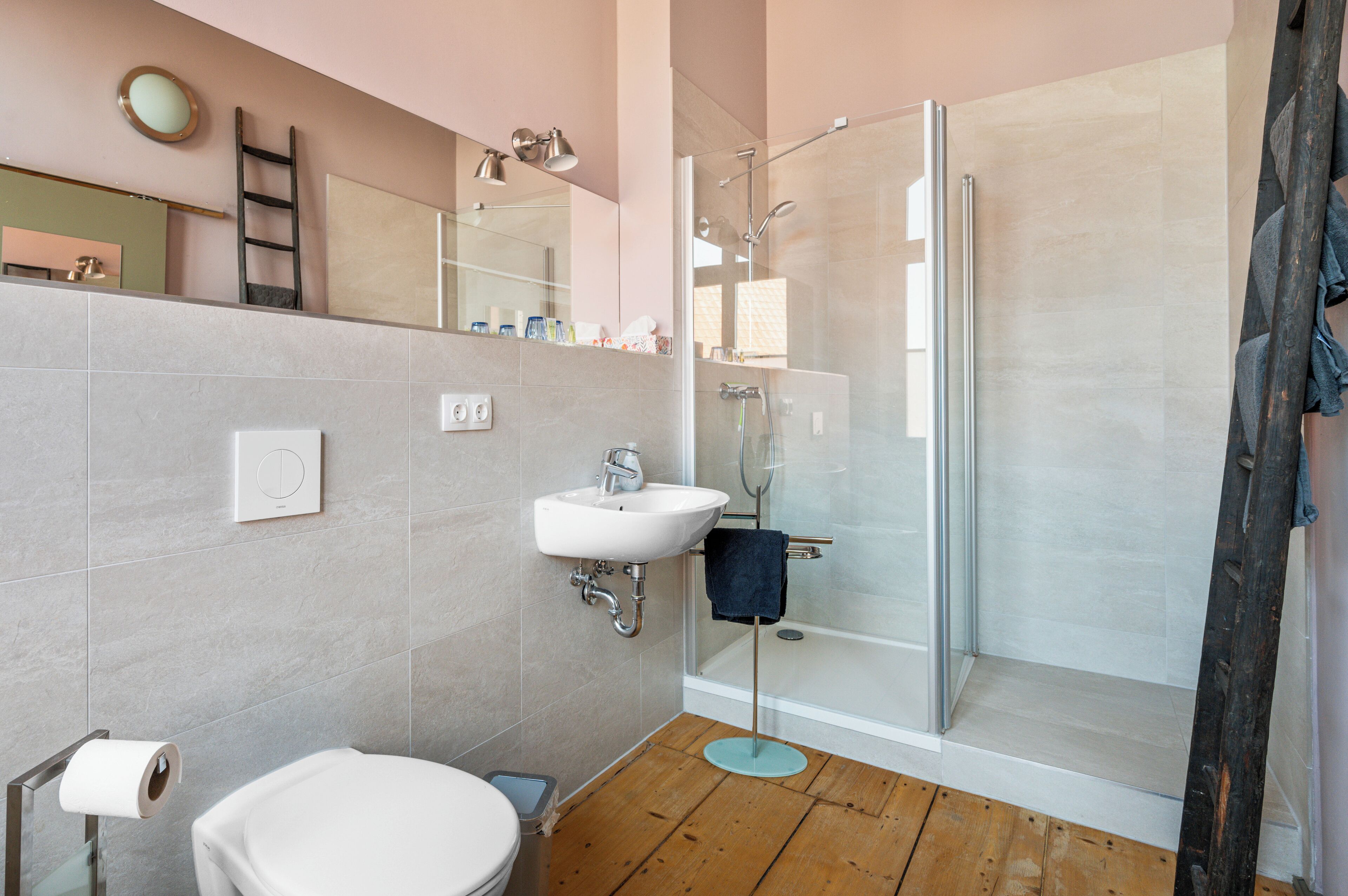 A modern bathroom with a shower, sink, and toilet.