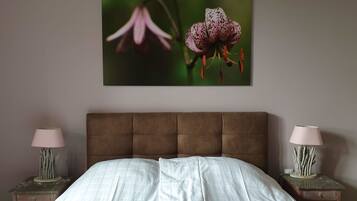 Una camera da letto con un letto grande, due comodini con lampade e un quadro di fiori appeso al muro.