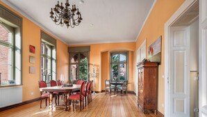 A dining room with a wooden floor, a chandelier, and a dining table with chairs. - Villa Bianca am Huy (Huy)
