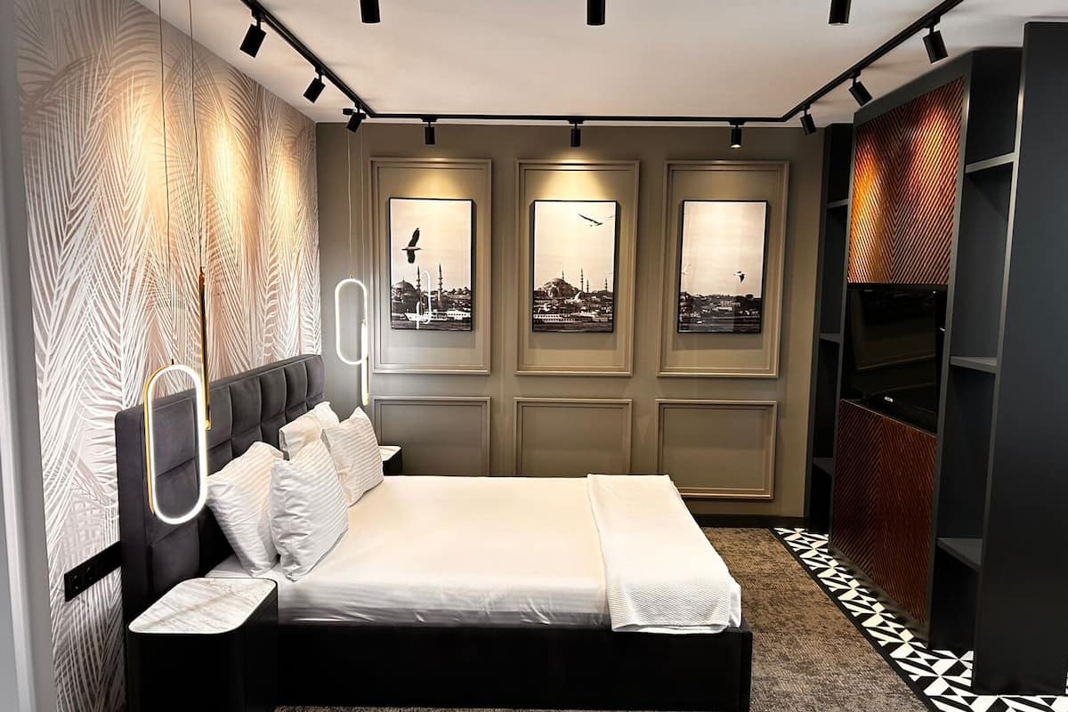 Une chambre à coucher moderne avec un lit, des œuvres d’art murales et un tapis à motifs.