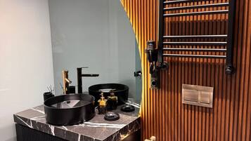 Une salle de bain moderne avec un meuble-lavabo aux lignes courbes, un évier noir et un mur recouvert de panneaux en bois.