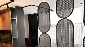 Un moderno vestíbulo de hotel con un piso de diseño geométrico, una recepción y una zona de estar con un sofá rojo.