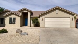 A single-story house with a beige exterior, a blue door, and a garage. - The Zion Getaway-Located in beautiful Southern Utah (La Verkin)