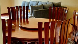 A dining area with a round wooden table surrounded by wooden chairs with cushioned seats. - Riverland Apartments (Nairobi)