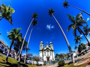 A church with two towers and a central dome, surrounded by palm trees and a clear blue sky.
