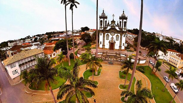 A plaza with a central fountain, surrounded by palm trees and buildings. - Hotel Pais e Filhos (São João del Rei)