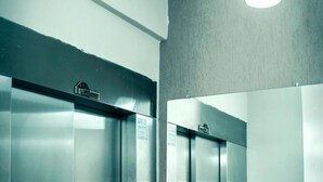 Two elevators in a modern building with metallic interiors and a simple, functional design. - Hotel Pais e Filhos (São João del Rei)