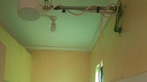 A small bathroom with a toilet, a shower head, and a window. - Small Villa Gardens (Kabati)