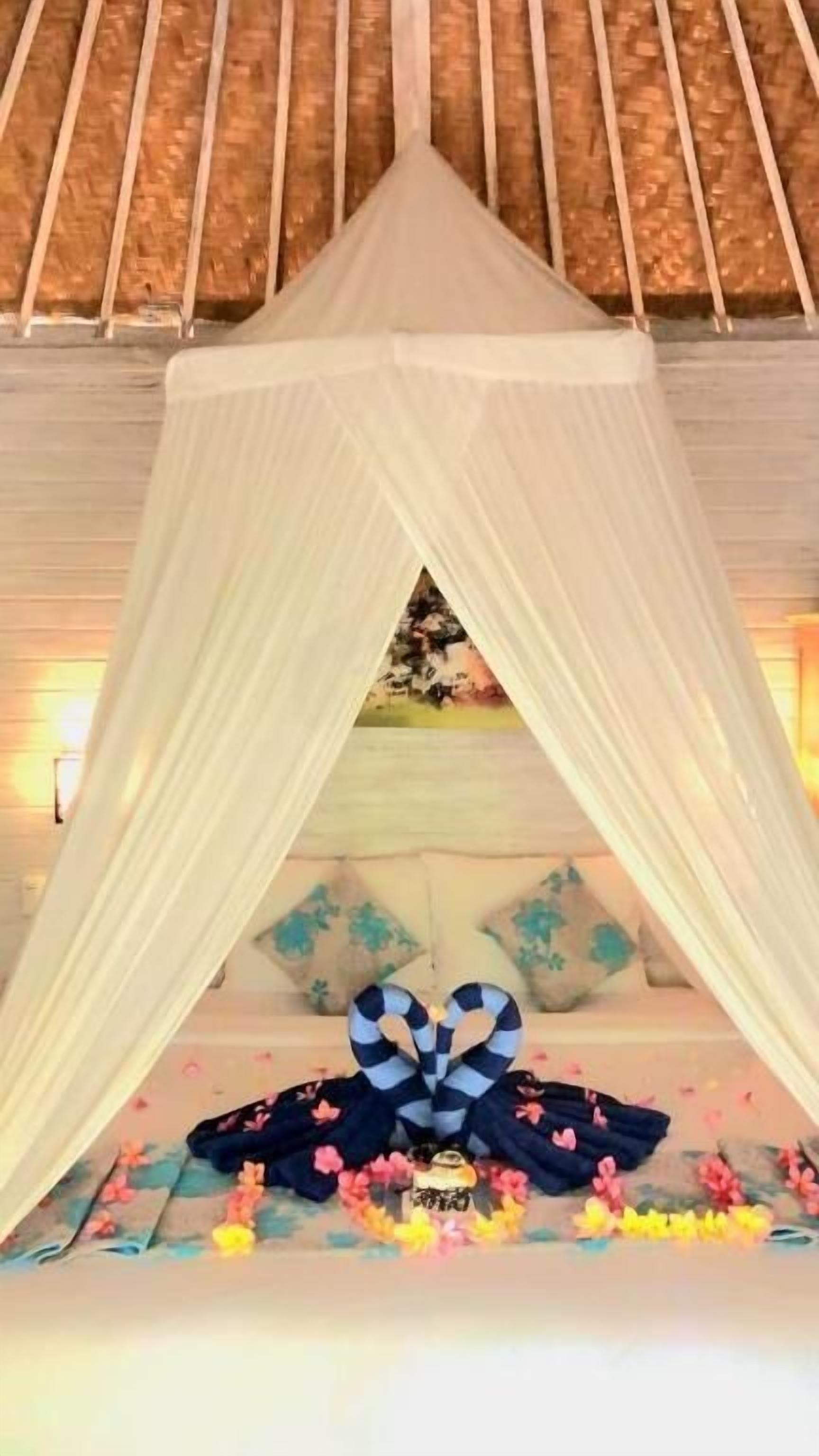 A room with a canopy bed, floral decorations, and a view of the outdoors.