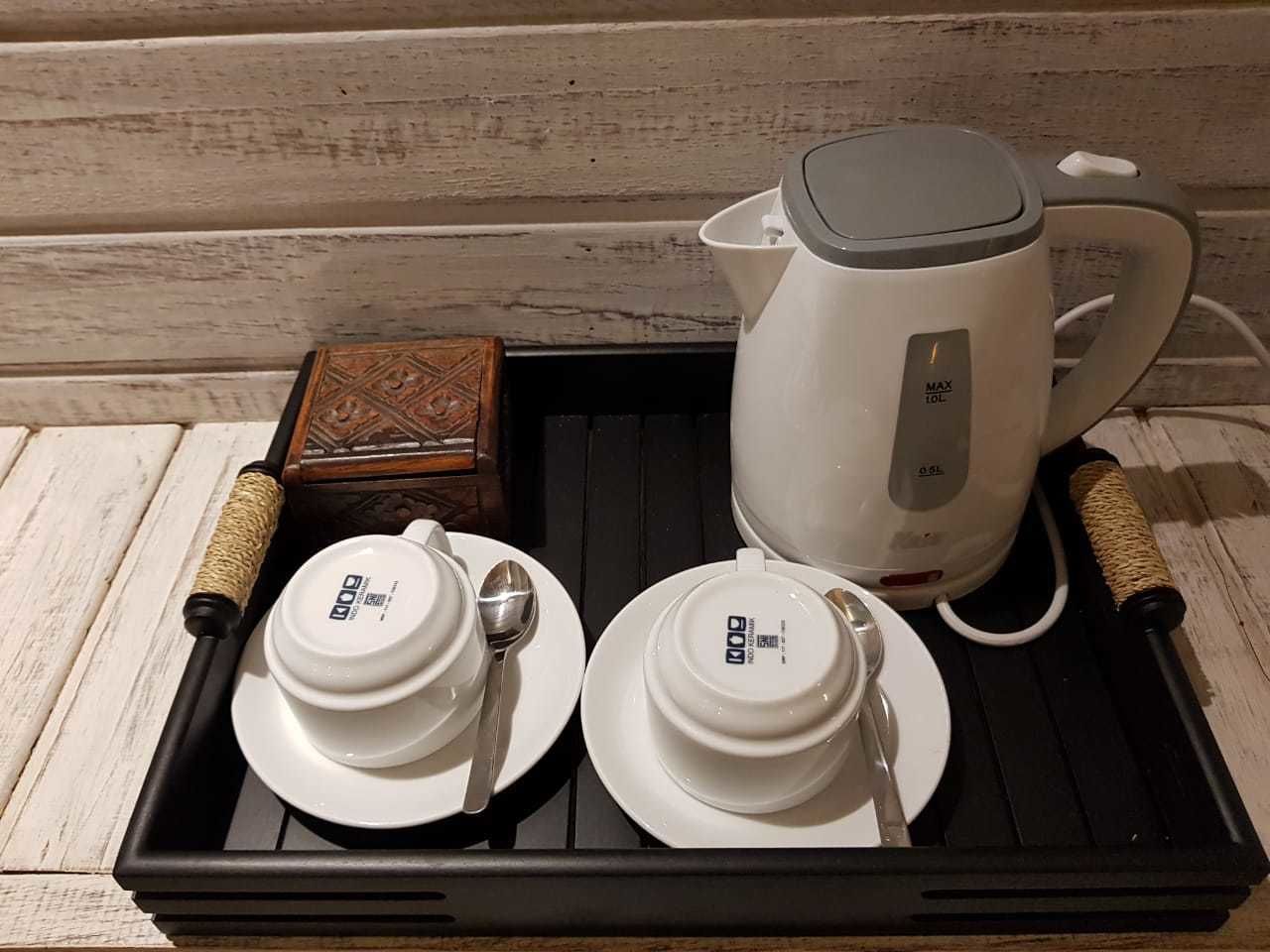 A tray with a coffee maker, two cups, a spoon, and a small box.