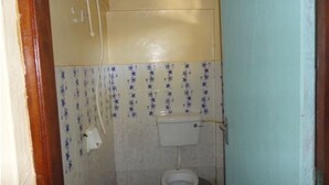 A small, narrow bathroom with a toilet and a wall-mounted sink. The walls are tiled with a pattern of blue stars. - Salmond View Hotel (Bungoma)