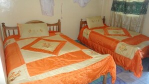 Two single beds with matching headboards and footboards, a wooden floor, and a window with a curtain. - Salmond View Hotel (Bungoma)