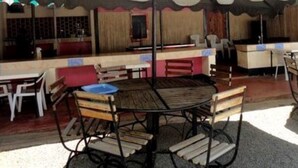 An outdoor seating area with wooden tables and chairs, a counter, and a view of the street. - Salmond View Hotel (Bungoma)
