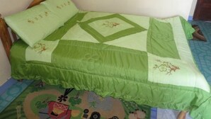 A bed with a green quilt and matching pillow, a wooden headboard, and a patterned rug. - Salmond View Hotel (Bungoma)