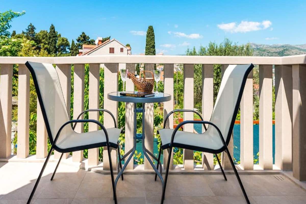 A balcony with two chairs and a small table, overlooking a scenic view.
