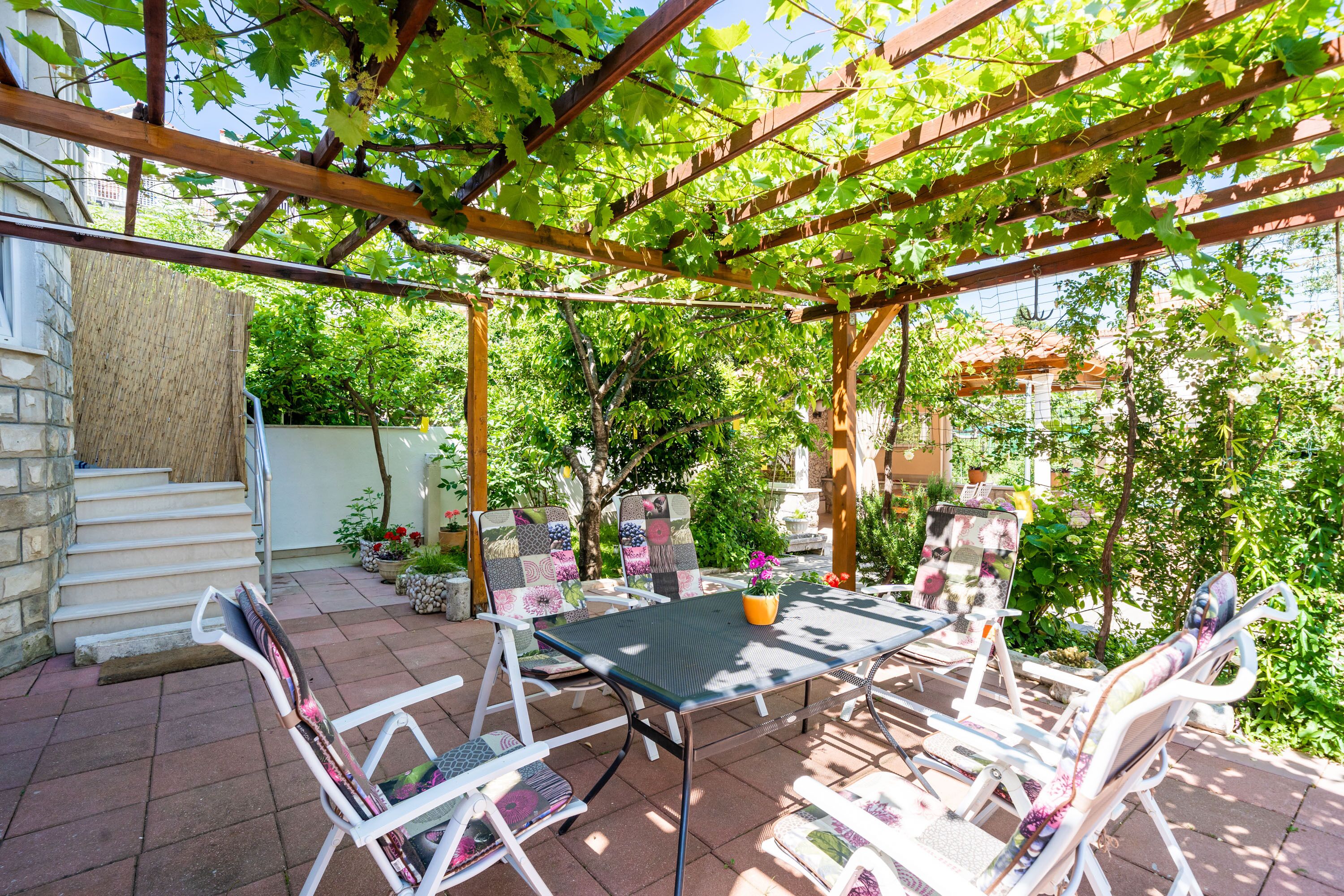 An outdoor patio with a pergola, a table, and chairs.