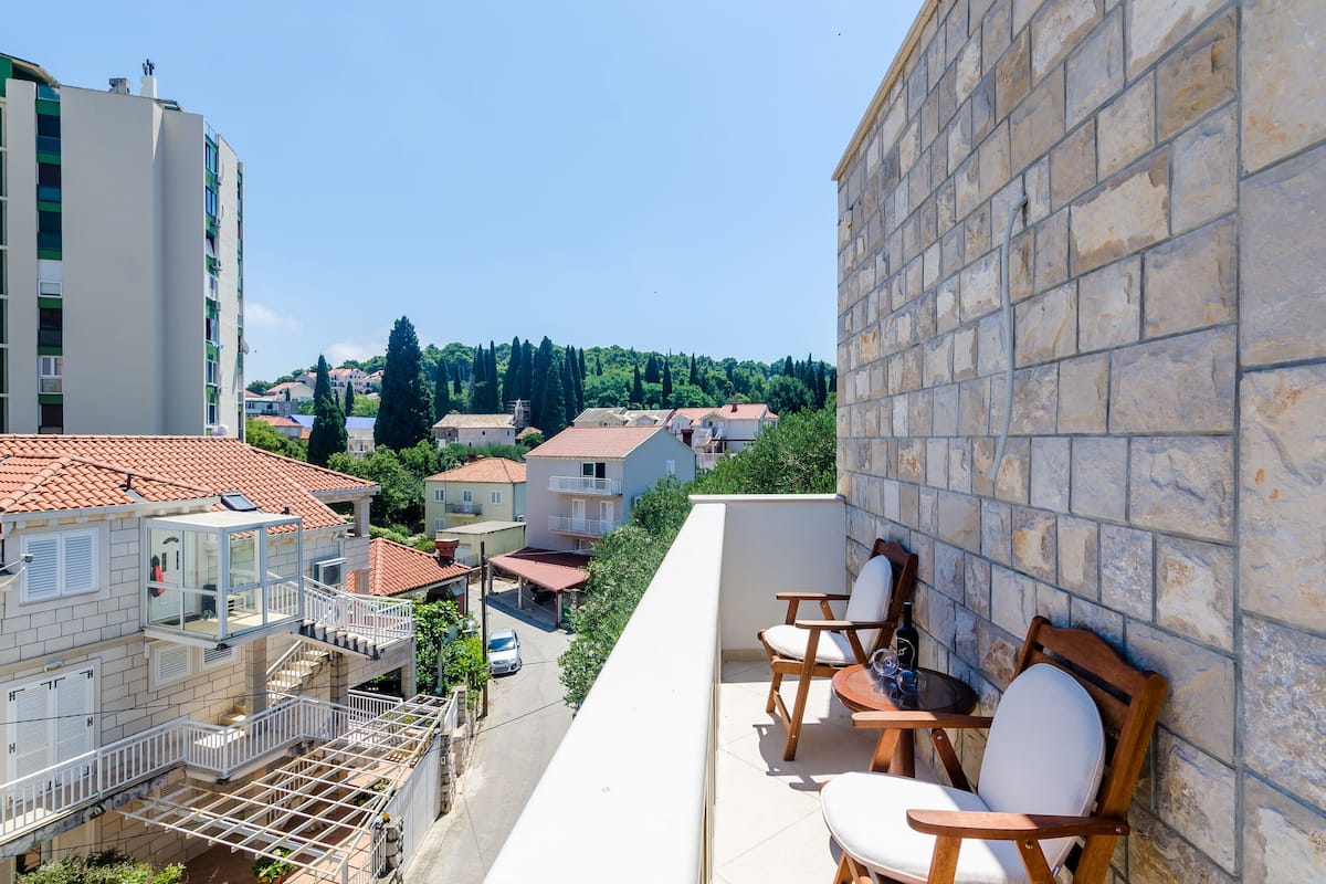 A balcony with a stone wall, a wooden chair, and a table.