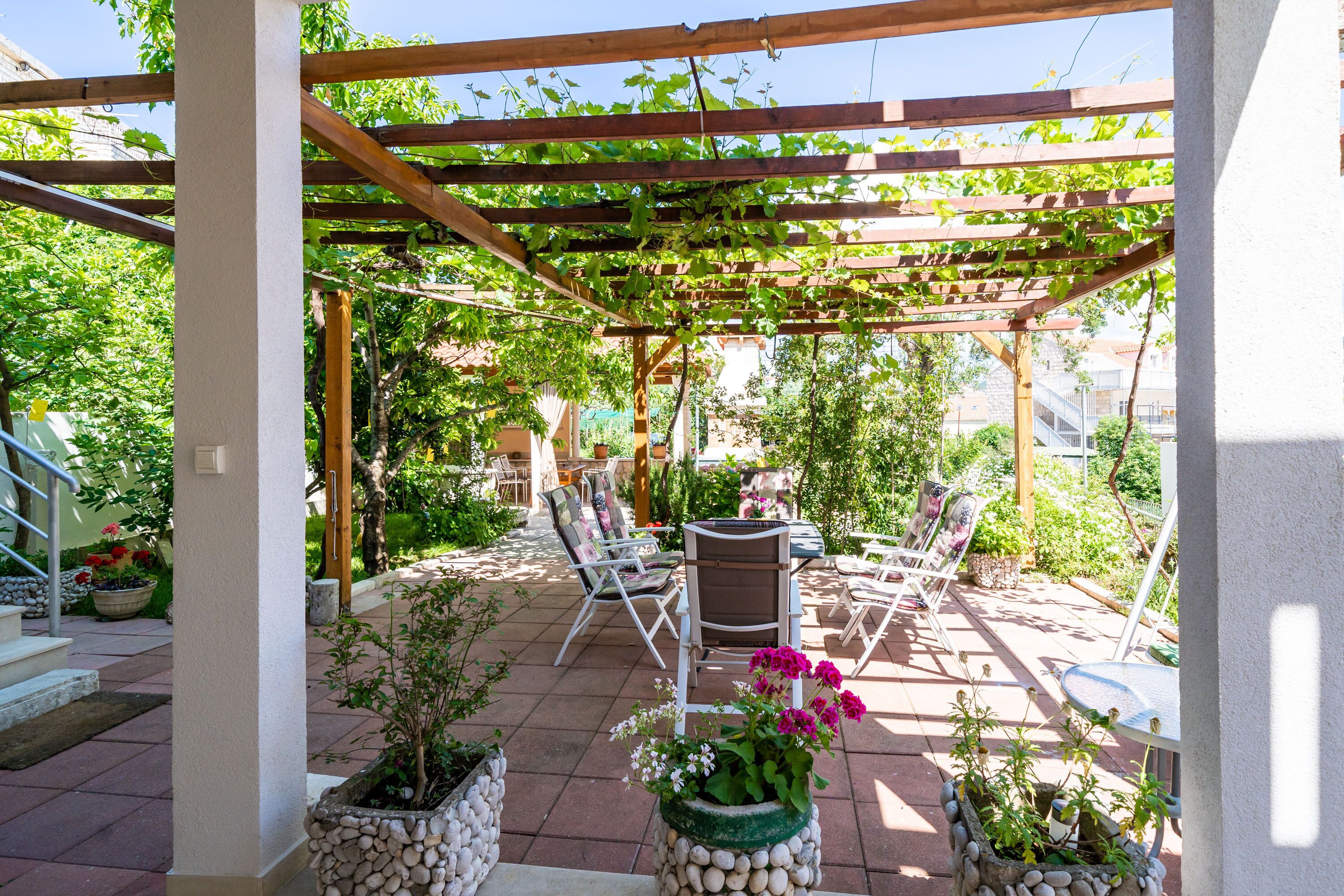 A covered patio with outdoor furniture and potted plants.