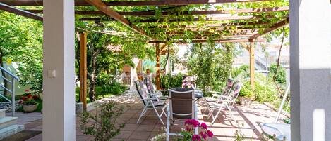 A covered patio with outdoor furniture and potted plants.