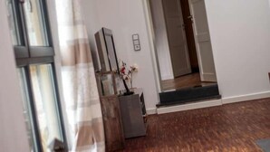 A room with a wooden floor, a window with a striped curtain, a wooden cabinet, and a door leading to another room. - Winzerhaus am Eckbach (Bissersheim)