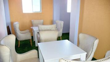A room with a white table and four beige chairs.