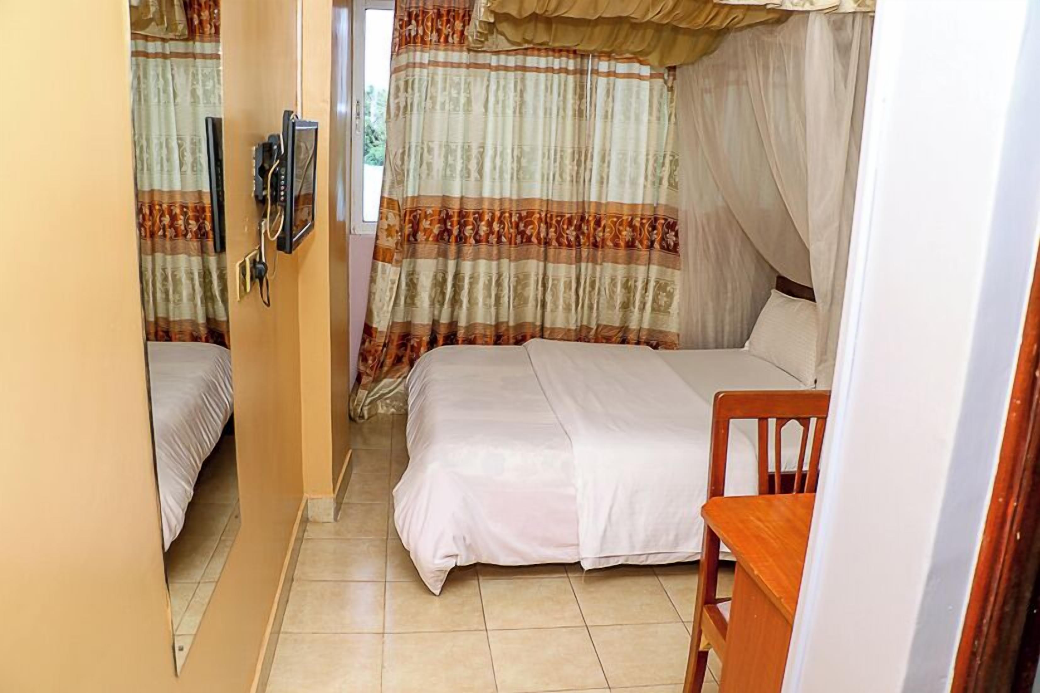 Een slaapkamer met twee bedden, een houten stoel en een nachtkastje.