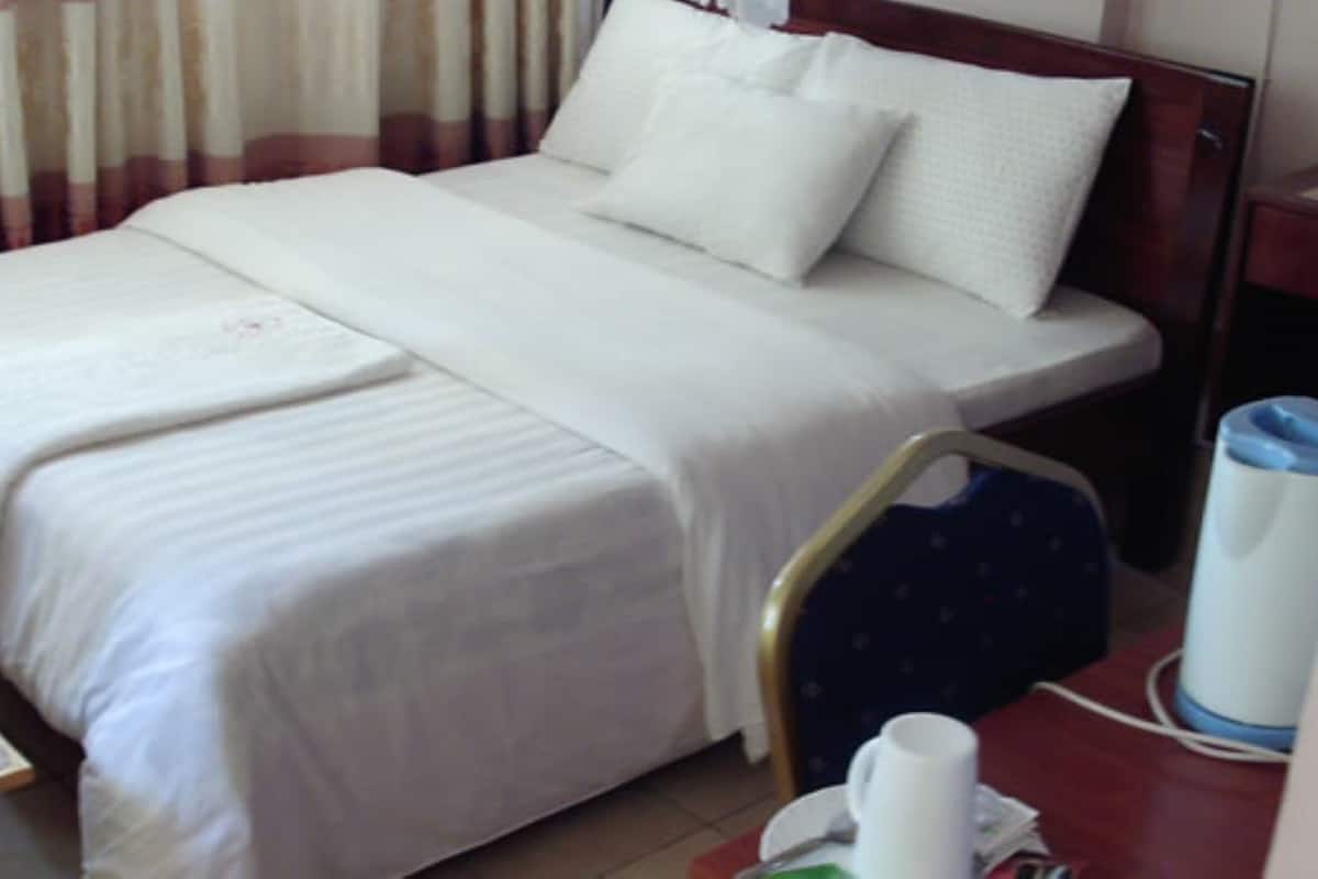 Ett hotellrum med en säng, en stol, ett bord och en vattenautomat.