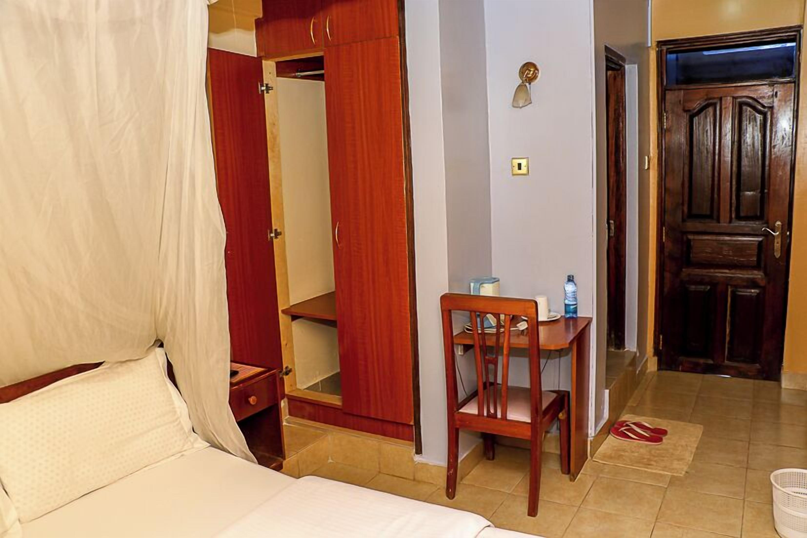 Una camera da letto con un letto, un armadio in legno, una scrivania con una sedia e una porta.
