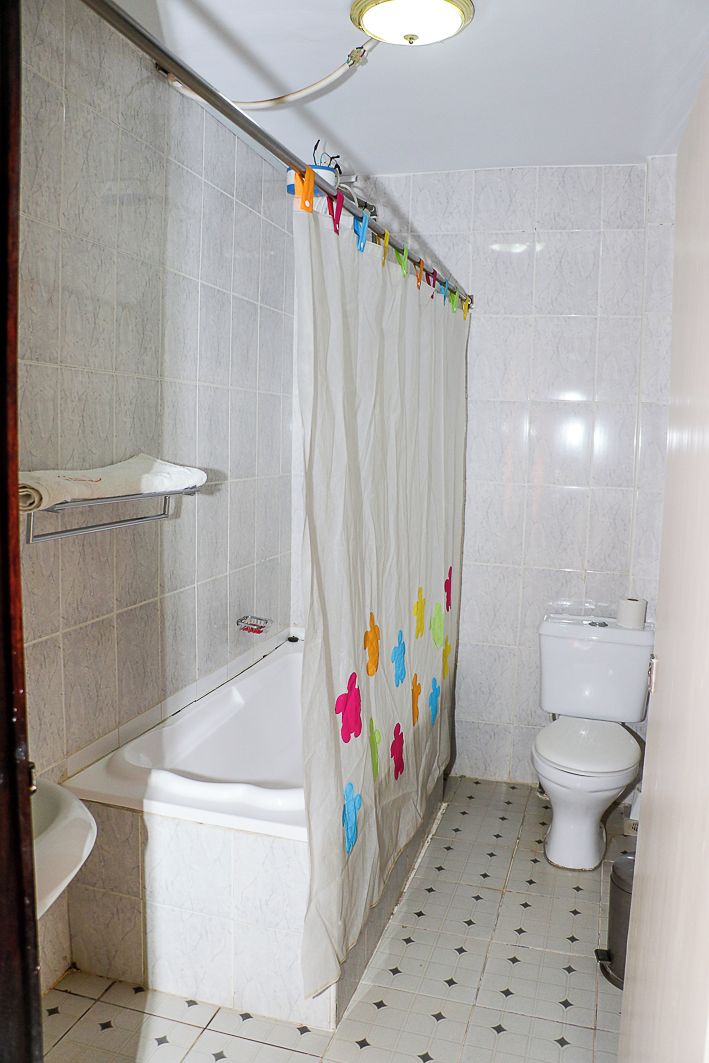 Un baño con cortina de ducha, inodoro, bañera y lavamanos.