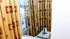Una habitación con cortinas estampadas, un ventanal y una mesa con un dispositivo.