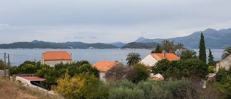 Un village côtier aux maisons en pierre, offrant une vue sur la mer et sur des montagnes lointaines.