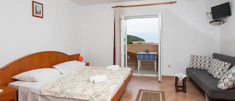 A bedroom with a bed, a sofa, a TV, and a balcony.