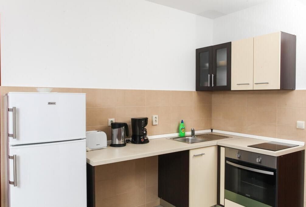 A compact kitchen with a white refrigerator, a coffee maker, a toaster, and a sink.