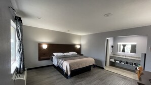 A hotel room with a bed, a desk, a mirror, and a window.