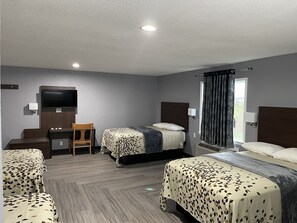 A hotel room with two beds, a desk, a chair, a TV, and a window with curtains.