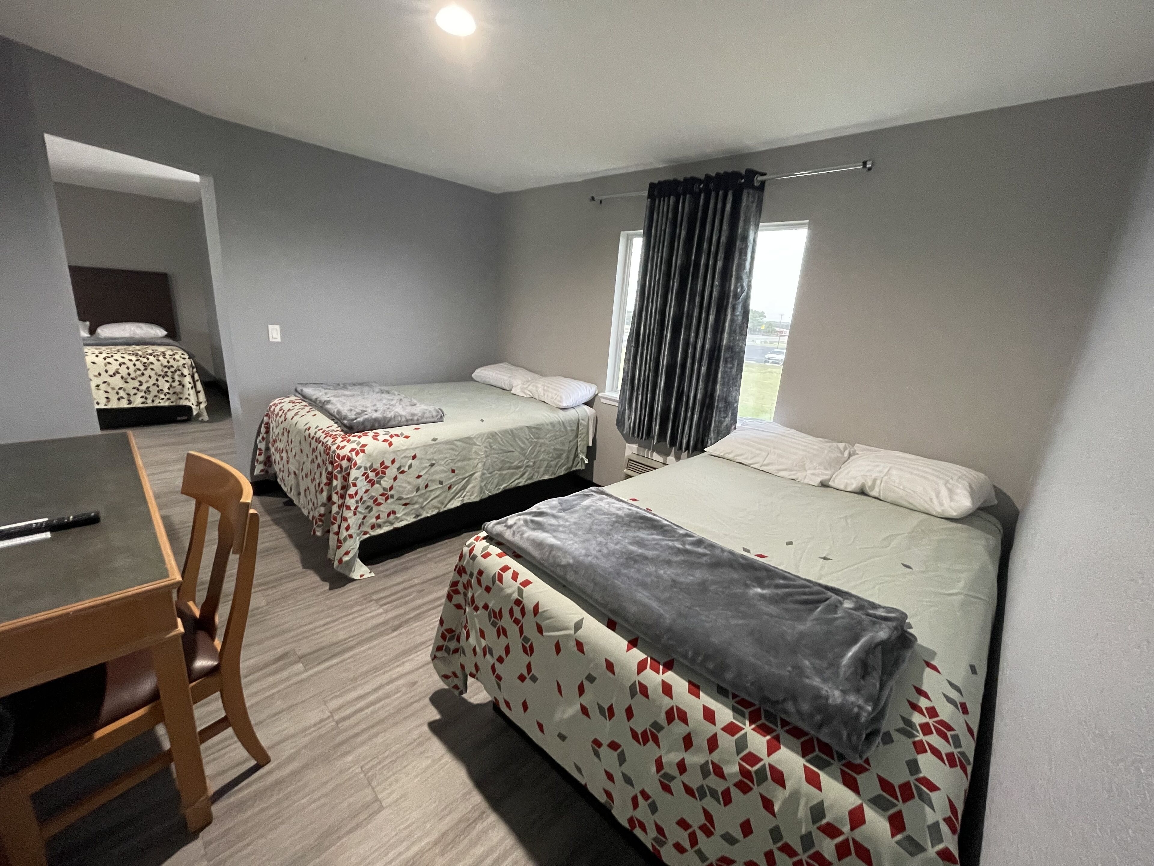 A hotel room with two beds, a desk, and a chair.