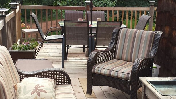 A wooden deck with wicker furniture, including two chairs and a table, under a red umbrella. - Chestnut Lane Bed & Breakfast - The Rose Room (New Glasgow)