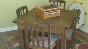 A dining table with chairs, a chessboard, and a patterned rug. - Chestnut Lane Bed & Breakfast - The Rose Room (New Glasgow)