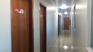 Un pasillo de hotel con puertas de madera, un cartel que indica el número de habitación 06 y un extintor de incendios montado en la pared.